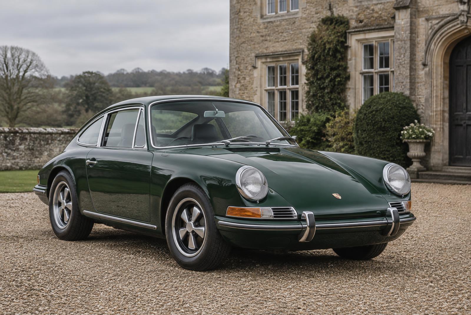 A green early Porsche 911 on the gravel drive of a stone country house